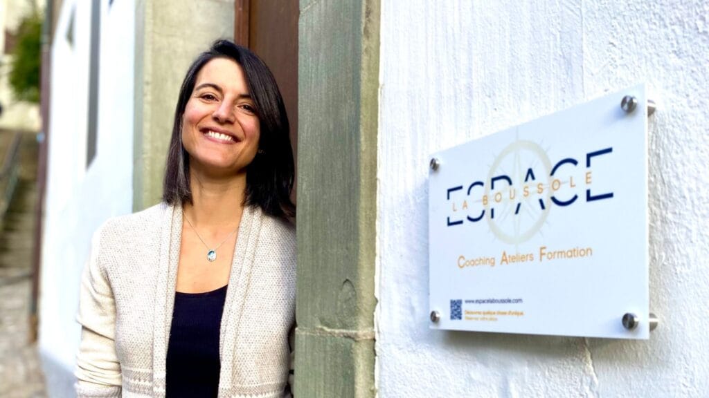 Portrait de Lisa Burri, fondatrice d’Espace La Boussole, debout devant l’entrée de son espace d’accompagnement à Fribourg. Cette image reflète l’accueil chaleureux et bienveillant réservé aux personnes en quête de clarté, de recentrage ou de mieux-être. Lisa y propose des accompagnements personnalisés en astrologie, Human Design, coaching de vie et nutrition, en présentiel à Fribourg ou en ligne. Cette photo illustre le lien humain et l’engagement dans un accompagnement sensible, concret et profondément aligné avec les besoins de chaque personne.